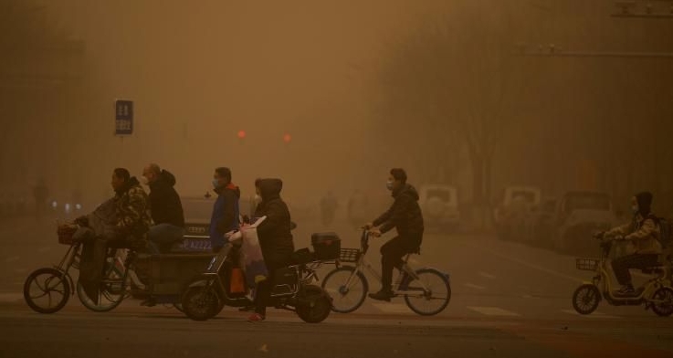 People crossing a street during a sandstorm in Beijing on Monday. AFP