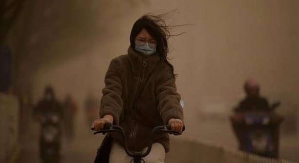 A woman cycles along a street during a sandstorm in Beijing on Monday. AFP