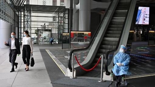 A worker wearing PPE guards the entrance of HSBC bank main Hong Kong office. AFP