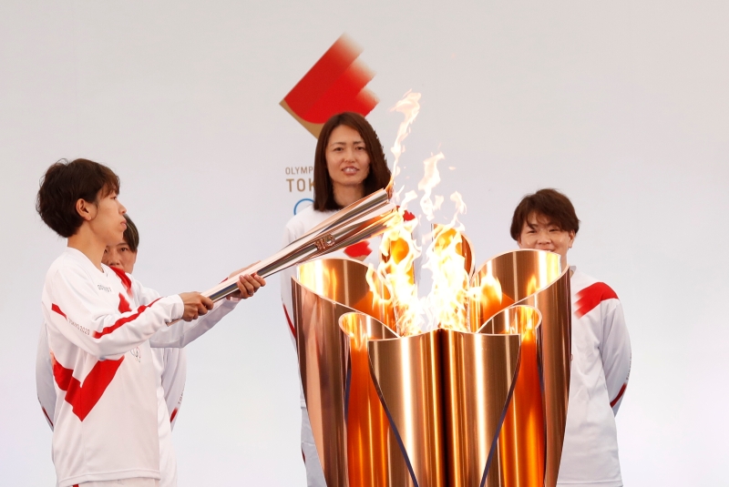 日本前女足队员岩清水梓（左）点燃手中的火炬。