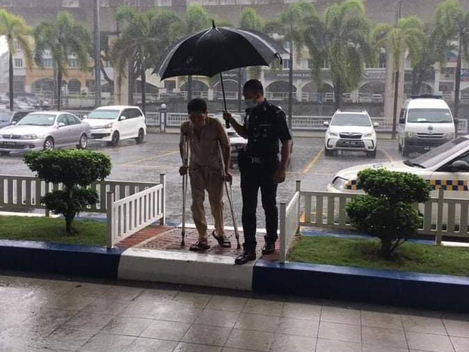 一名警察在雨中为残障人士撑伞，场面感人。（照片取自纳吉脸书）