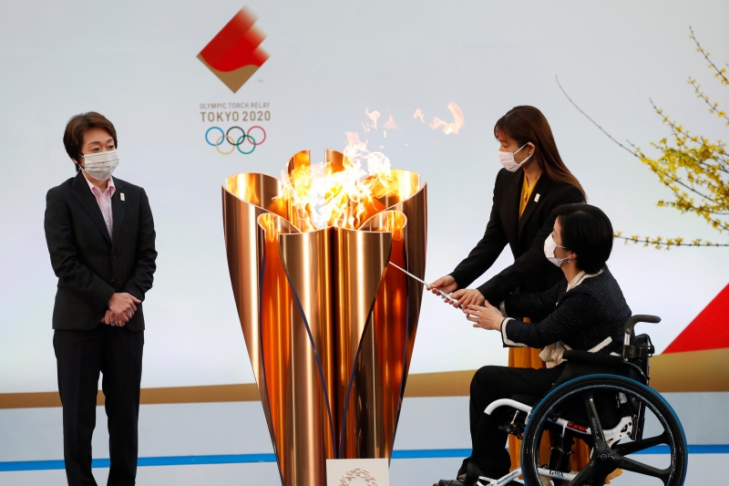 东京奥组委主席桥本圣子（左起）见证奥运火炬传递大使石原里美和残奥会女子射击选手田口亚希，共同点燃了圣火盆。（美联社照片）
