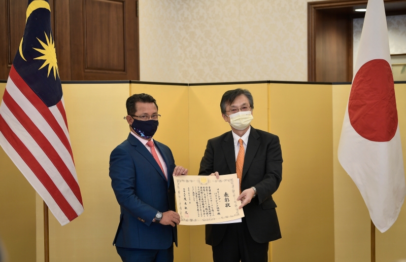 日本驻马大使冈浩（右）颁发“日本外交部长表彰奖状”给大马羽球总会，由大马羽总会长丹斯里诺萨代表接领。