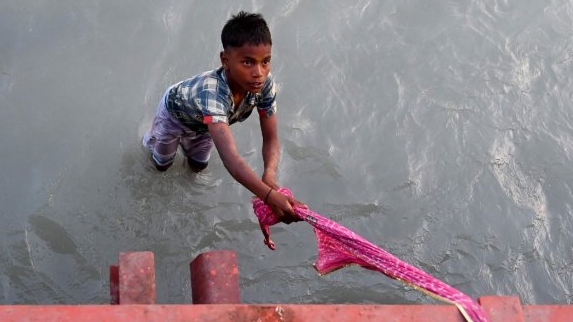 A boy waits to catch offerings thrown by Hindu devotees in Ganges. AFP