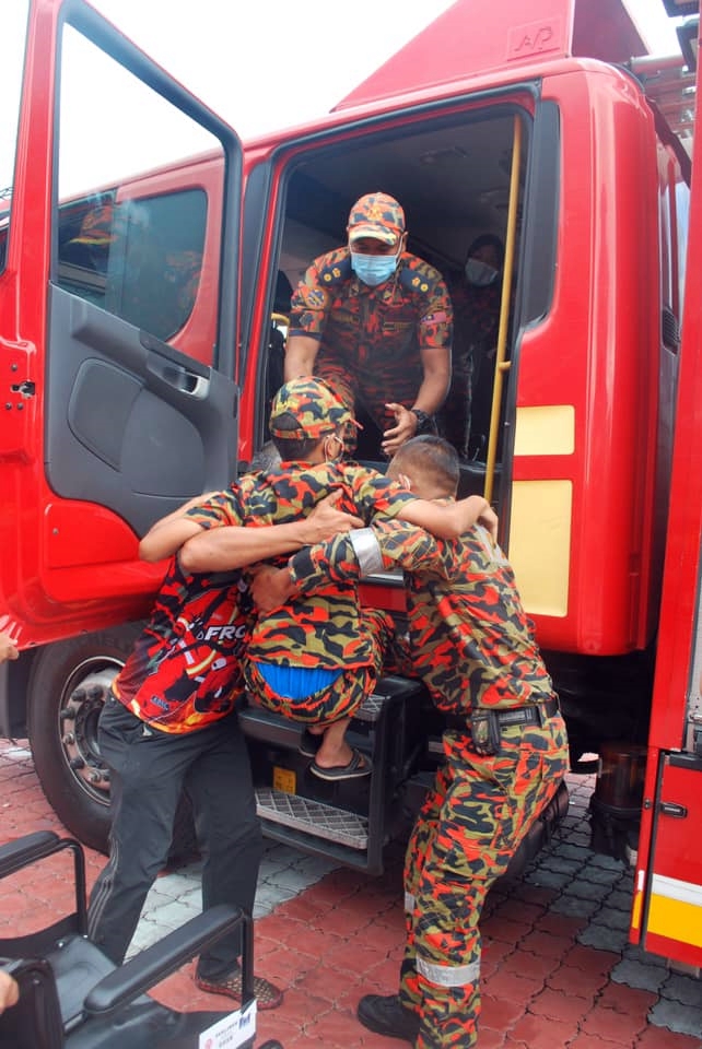 消防员合力把阿克马抱上消防车。（取自玻州消拯局脸书）