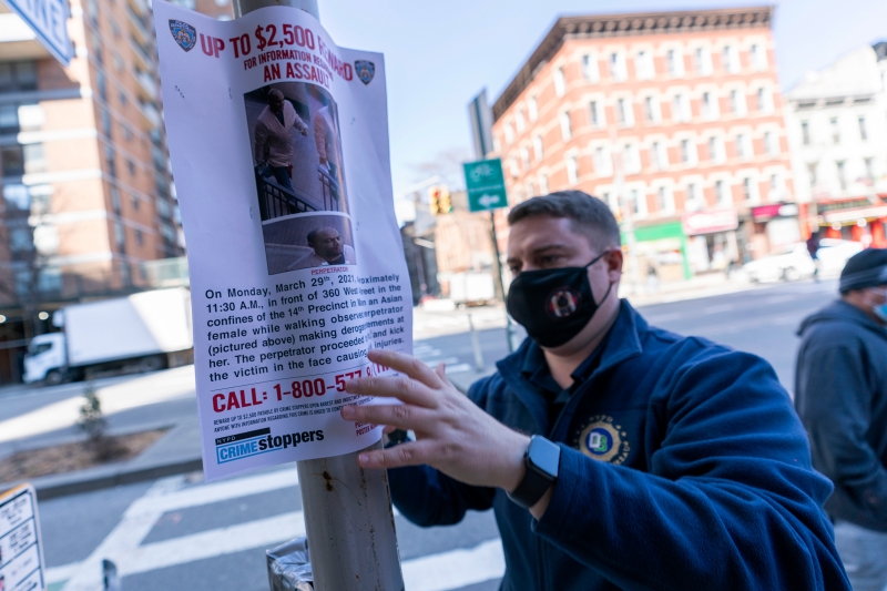 纽约市警员周二在事发现场附近的街头张贴悬赏提供攻击亚裔妇女嫌犯消息的海报。（美联社照片）