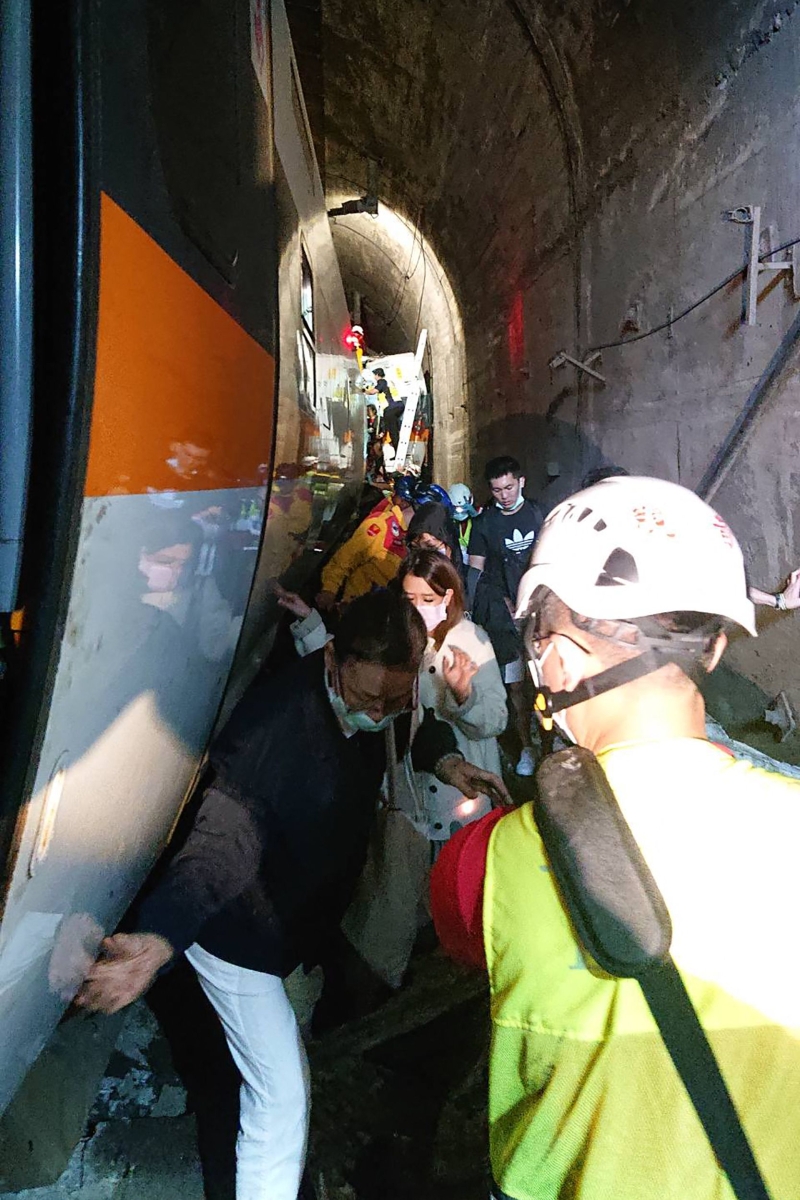 逃过一劫的生还乘客在警消人员协助下，从狭窄的通道中陆续离开隧道。（法新社照片）
