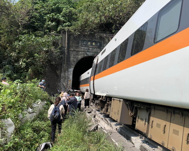 事发隧道前，一些脱困的乘客在列车旁等待消拯人员下一步的指示。（图片 新华社）