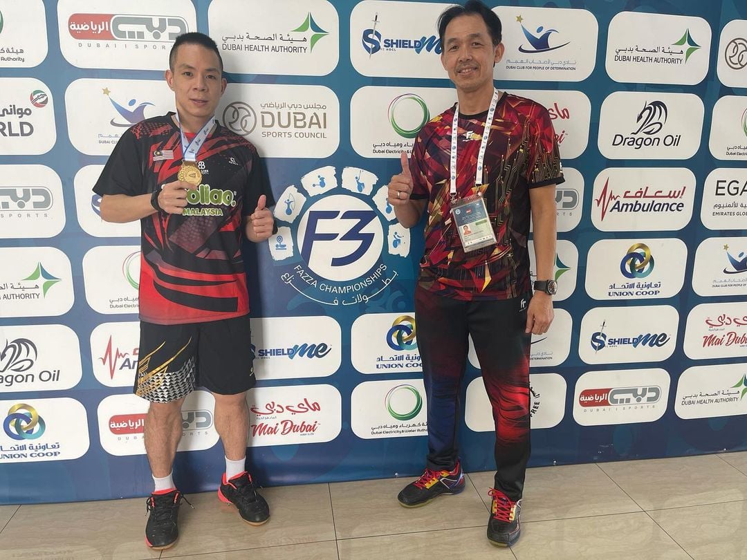 谢儮好（左）在迪拜残疾羽球国际赛接连击败世界第3的苏约和世界第1的迪瓦夺得SU5（上肢残疾）级别男单冠军，这让他很有机会在东京残奥会摘金。图为他在赛后与教练拉锡合影庆祝胜利。（谢儮好IG照）