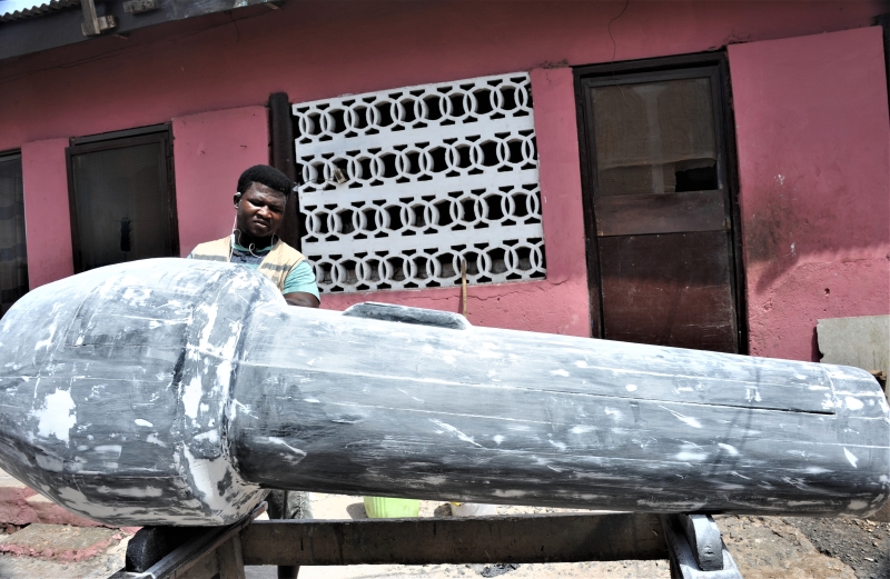一名工匠在加纳首都阿克拉主城区一家棺材铺里为一副麦克风造型棺材抛光。（图：新华社）