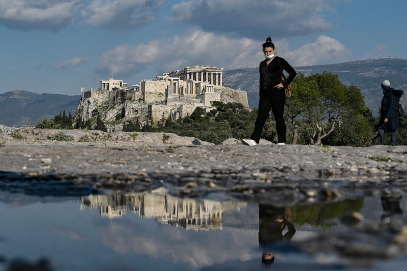 为游客必游之地的雅典卫城倒映在水中。希腊露天考古遗迹上月起恢复开放，但少了外国游客，许多古迹都冷冷清清。（图：法新社）