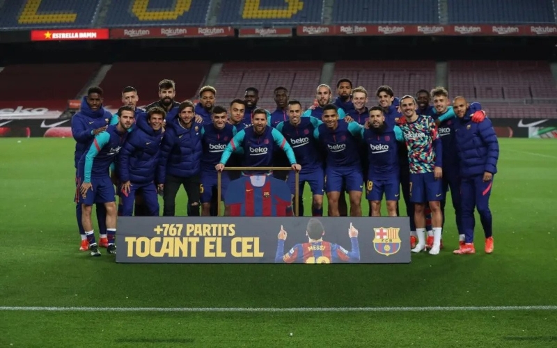 巴塞罗那在赛前为成为队史出赛王的梅西（中）举办纪念仪式，图为梅西手持纪念球衣与队友们合影。（巴塞官网图）