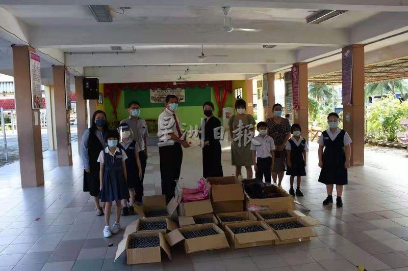 RX United Sdn Bhd的代表兼市政四小学生家长刘莉霞（中）昨早赠送喷雾消毒液与环保袋给该校986名学生和教职员，由校长林以善（右七）代表接收；校方颁赠感谢状予该公司。
