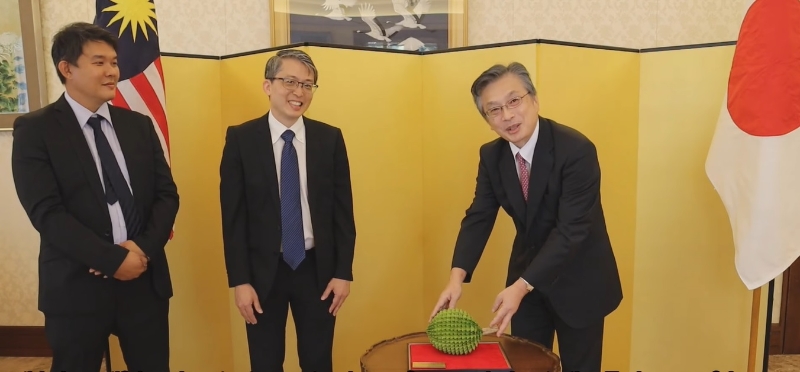 叶国林（左）特别折叠出自己设计的折纸榴莲，赠送予日本驻马大使冈浩（右）。中为庄诒钧。