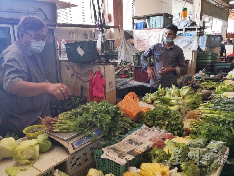 李金明（左）指雨季导致一些蔬菜产量少，以致近这两周有一些菜类都涨价了。
