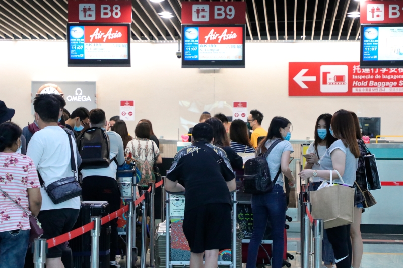 因疫情滞留澳门多月的大马人和新加坡人周四在澳门机场办理登机手续。(美联社照片)