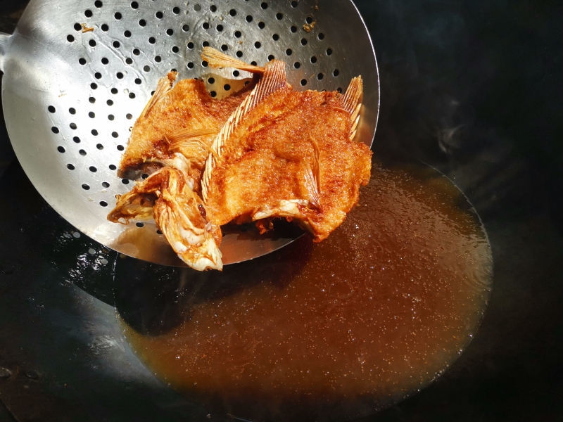 将打理干净的鱼从肚子内部切开，不切断、脊背相连，然后两面切花刀并将鱼翻开，码上盐、料酒、胡椒粉、生姜片，腌制30分钟。然后将鱼炸至金黄捞起。