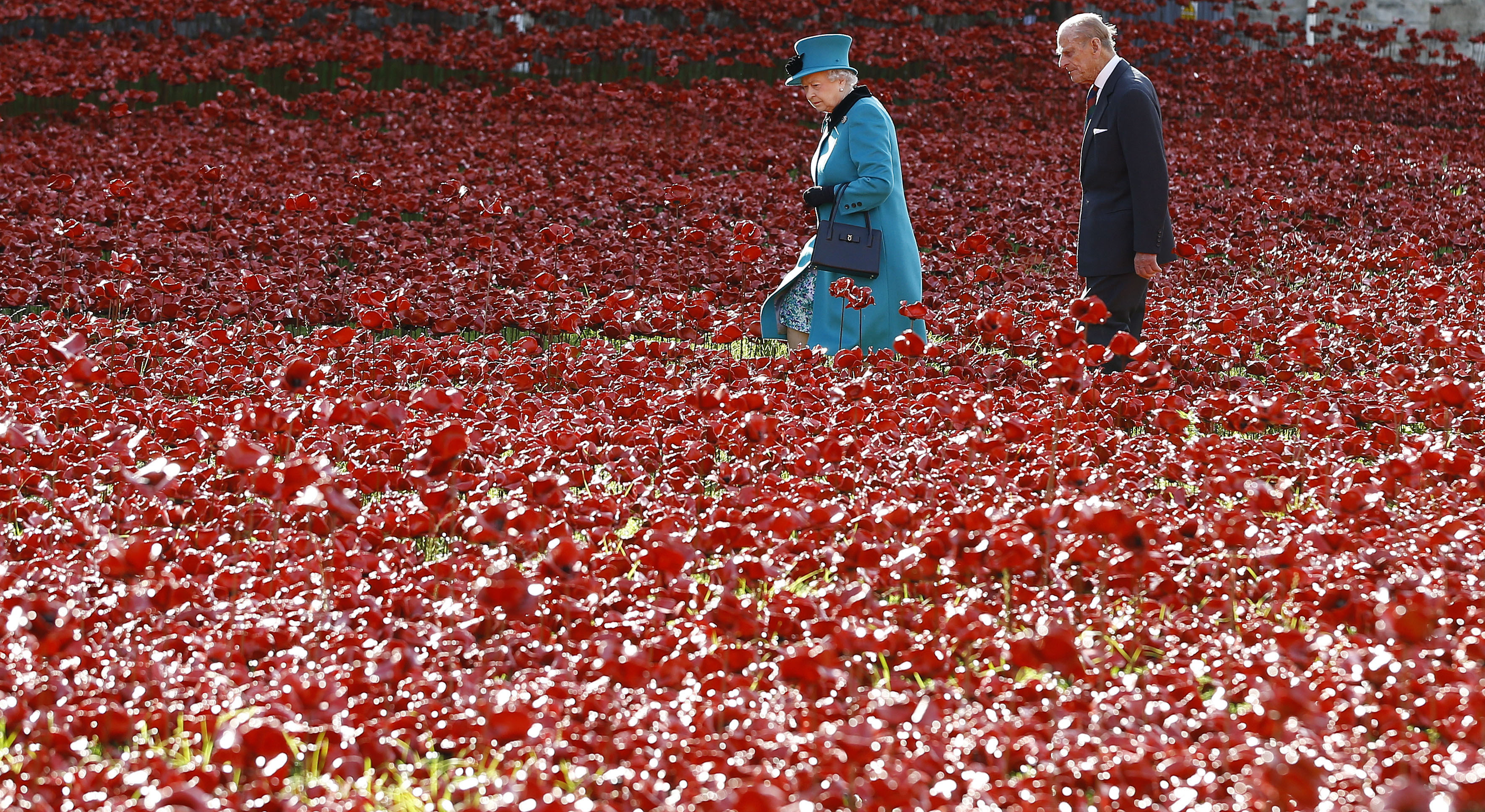 这是在2014年拍摄的照片，英国女王伊丽莎白二世在和菲腊亲王在伦敦参观陶瓷罂粟花田。