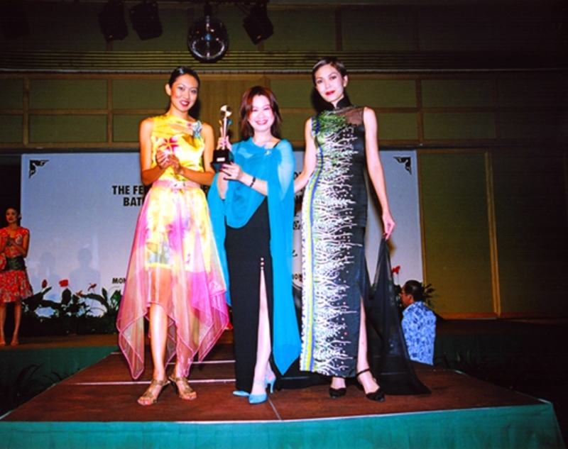 2005年，丘玉凤在全国芭迪女装设计创作比赛中荣获冠军，身边两名模特儿穿的就是她设计的服装。