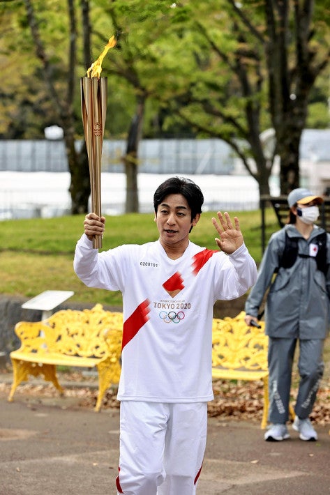 歌舞伎演员片冈爱之助周二在大阪以第一火炬手身分传递圣火，图为他挥手致意。（网络照）

