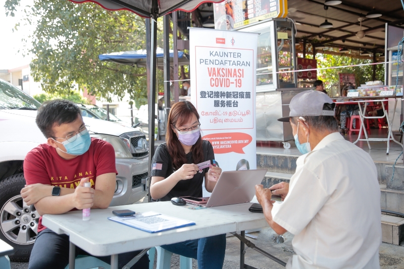 崔慈恩（中）替市民登记疫苗接种。左为怡保东区国会议员政治秘书张迪翔。