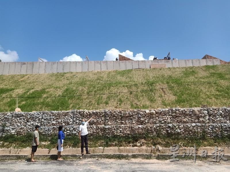 谢保恒（右）所站之处，就是发展商在万利花园进行的山坡挡泥墙。