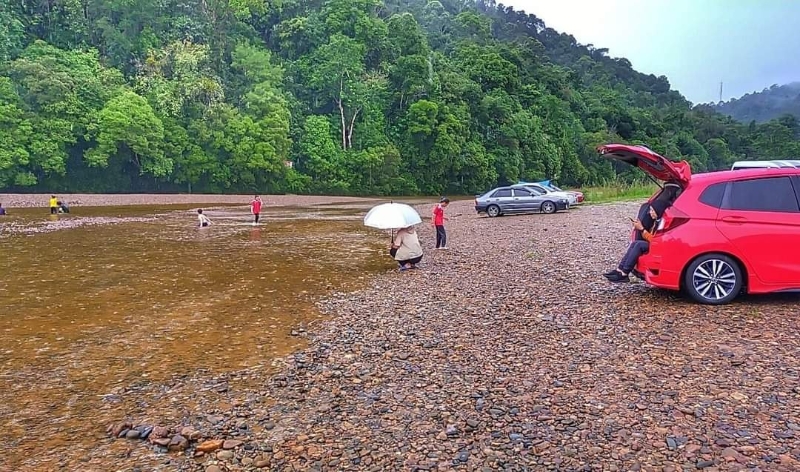 民众将车子停放在滩边，迫不及待下水感受大自然。
