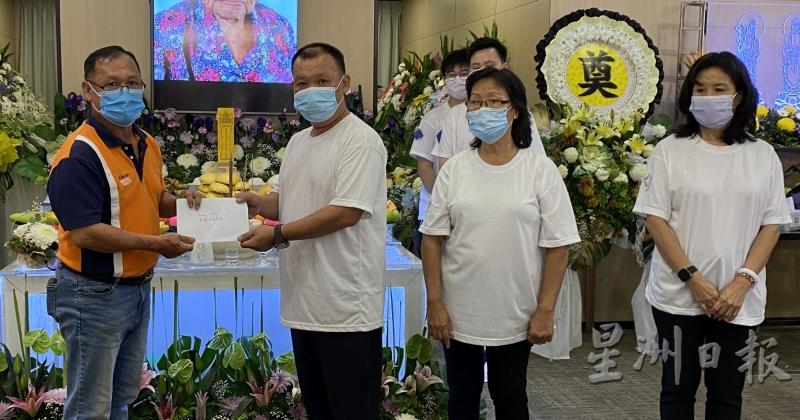 峇樟慈善基金代表（左一）接领家属的捐款，右一为周玉清。
