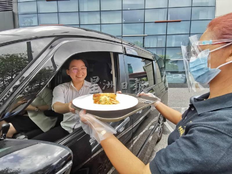 餐厅员工依据标准作业程序将食物送到顾客车上。