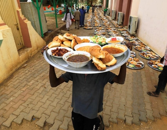 一名男子托举开斋饭从苏丹首都喀土穆一条街道经过。
