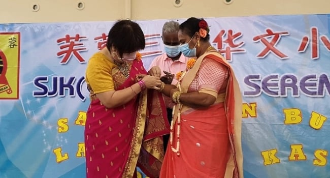 Headmistress Yan Shu Xia (L) presents a gold bracelet to Puspa.