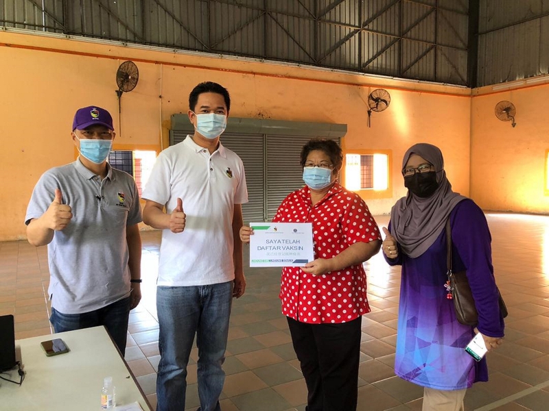 张聒翔（左二）巡视希盟甘榜英达新村管委会及甘榜英达睦邻计划联办的登记接种疫苗活动，并与前来登记接种的村民合影。左一为赖振耀。

