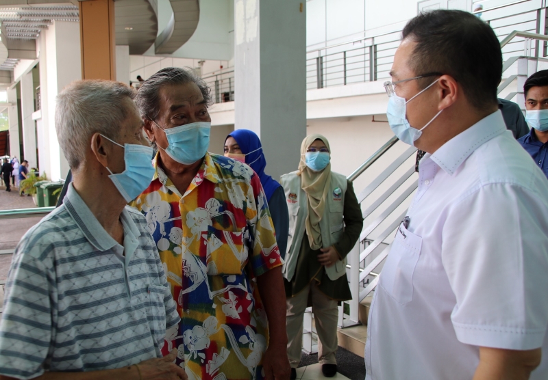 郑亚兴（82岁，退休人士）在老邻居陈均平（75岁）陪同下报到，但他向医护员表示不舒服，暂不接种；右是林桂亿。