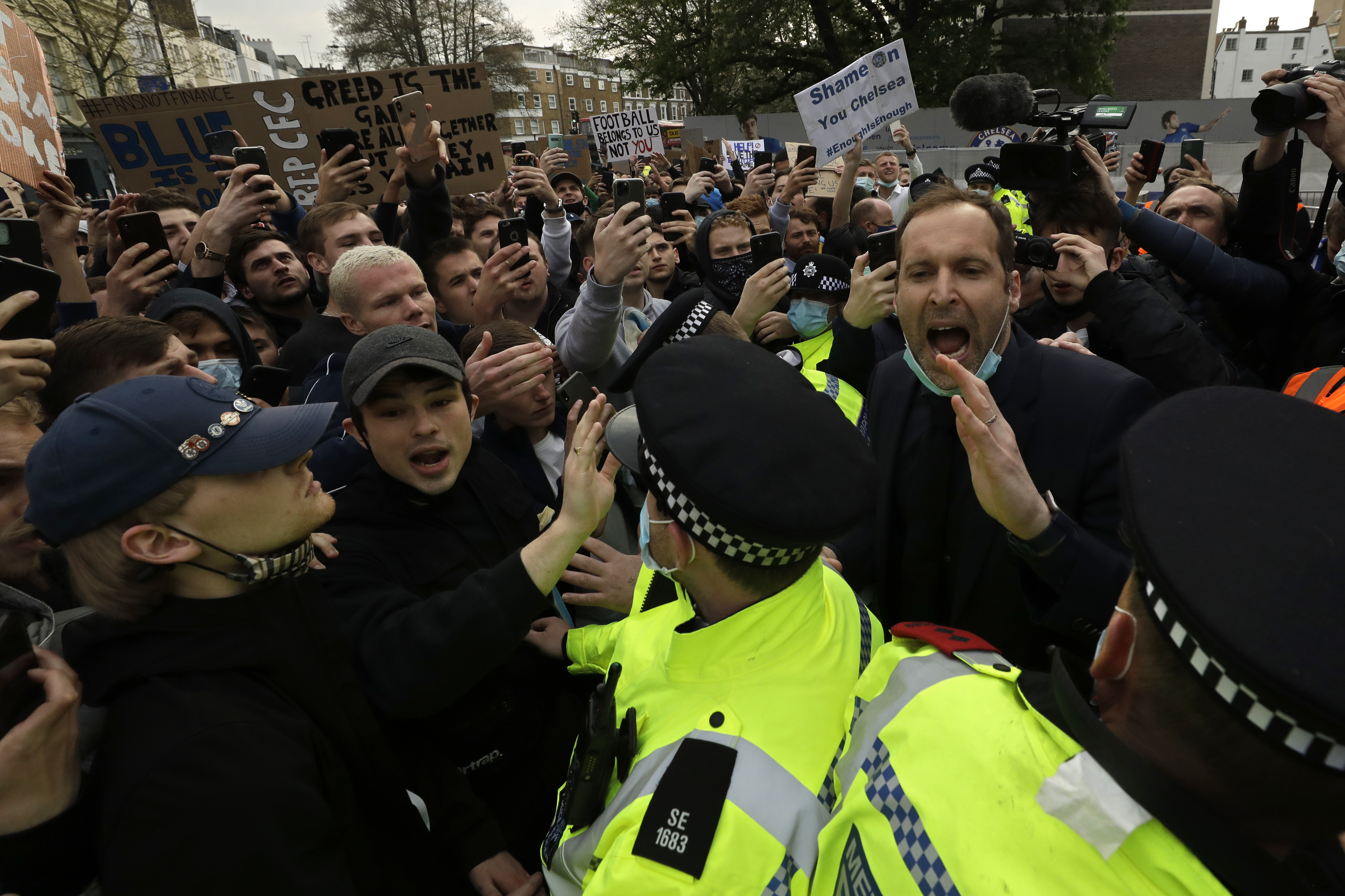 愤怒的切尔西球迷聚集在史丹福桥球场外抗议球会参加欧超联 ，在一群警察后面的切赫（右） 试图平息球迷们，他还被骂“叛徒”。（美联社照片）

