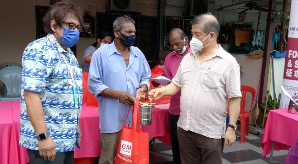 Lim Soon Peng (R) handing a 3-tier tiffin box filled with food to a beneficiary. On the left is the association's executive advisor Tan Sri Syed Mohd Yusof.