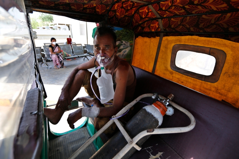 印度艾哈迈达巴德一名冠病患者，被迫在自己的三轮车内吸氧，等候政府医院腾出病床床位，让他入院治疗。（美联社照片）