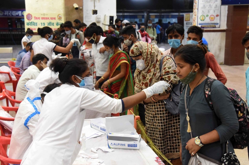 在印度巴特那的火车站，医务人员为民众进行冠病病毒检测取样。（新华社图片）