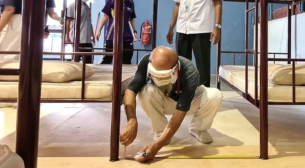 A volunteer measures the distance between beds as required by the health authorities. SIN CHEW DAILY