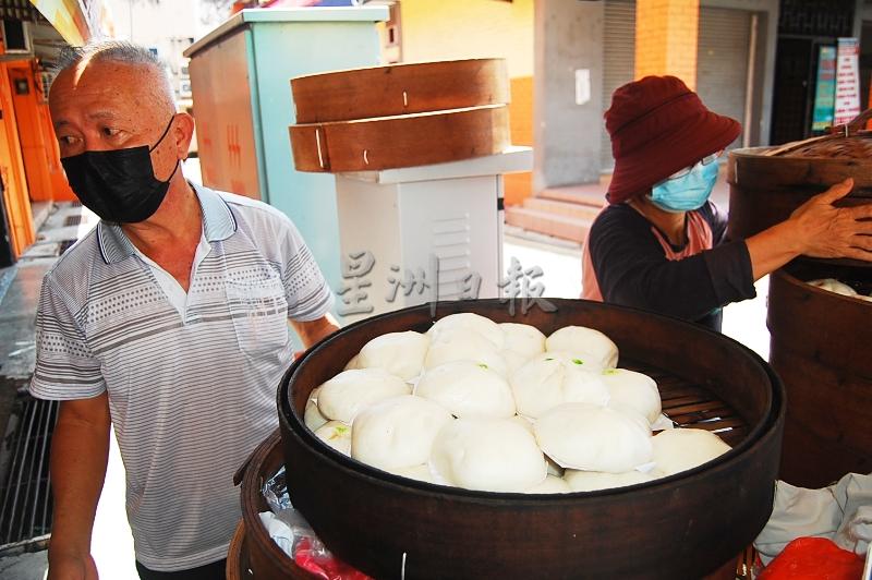 吴茂江夫妇在包档前忙碌为顾客包好包点，让他们带回工作地点，口碑因而获得广传。