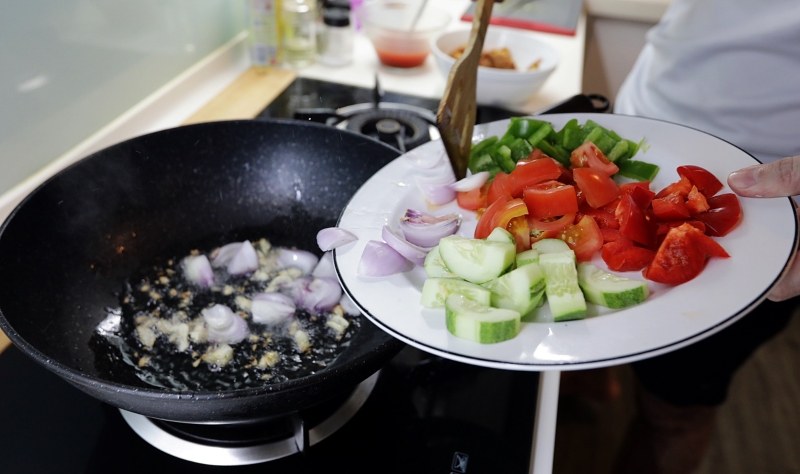 爆香蒜片，接着加入大葱、黄瓜、灯笼椒炒一炒，最后加入番茄。