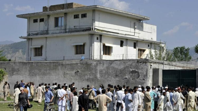 Journalists and local residents gather outside bin Laden's hideout after his death. AFP