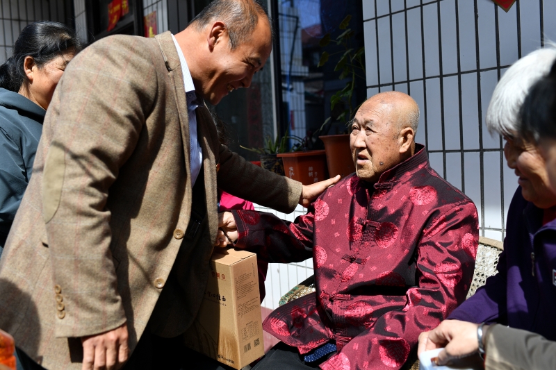 柳林县委老干部局的工作人员（左）看望胡在忠老人，送上祝福。（图：新华社）