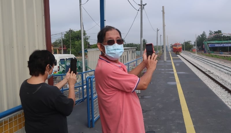 郑德源和太太张慧英在昔市临时火车站，拍摄火车使用高轨入站的画面。