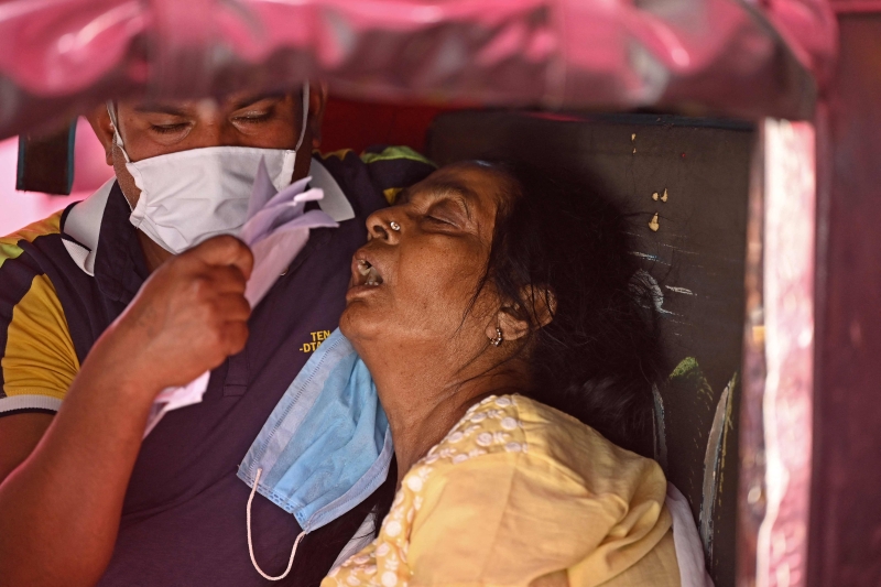 加济阿巴德一座锡克教庙外，一名女患者坐在三轮车上等待接受免费输氧。（法新社照片）

