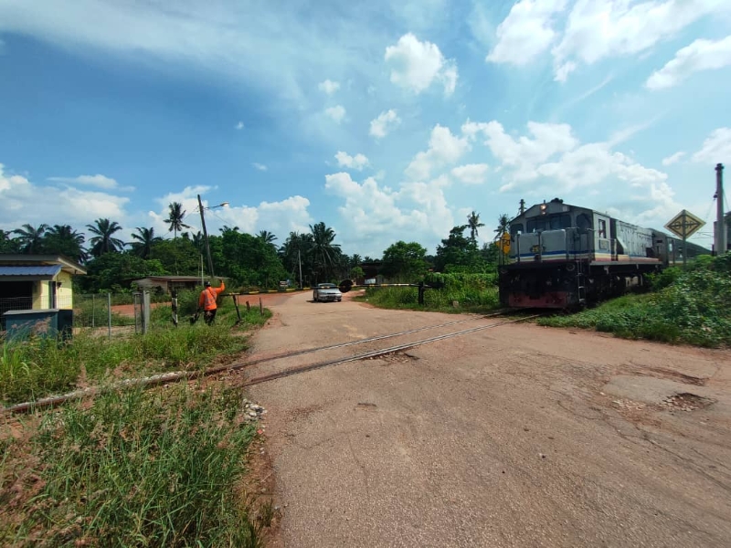 一列火车在守栅门协助下，经过金马士峇鲁火车栅。