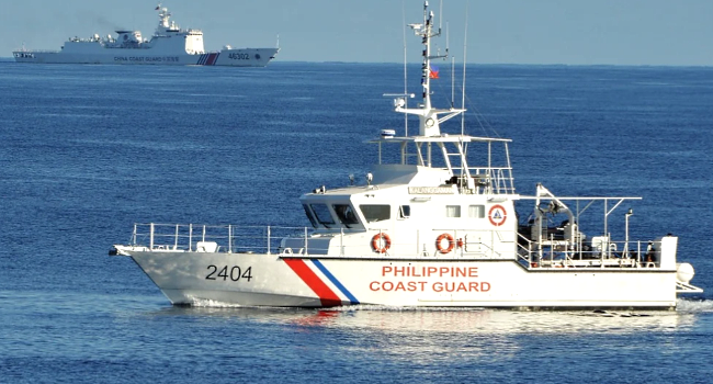 A Philippine coastguard ship is seen sailing past a Chinese coastguard ship near Scarborough shoal, in the South China Sea. AFP