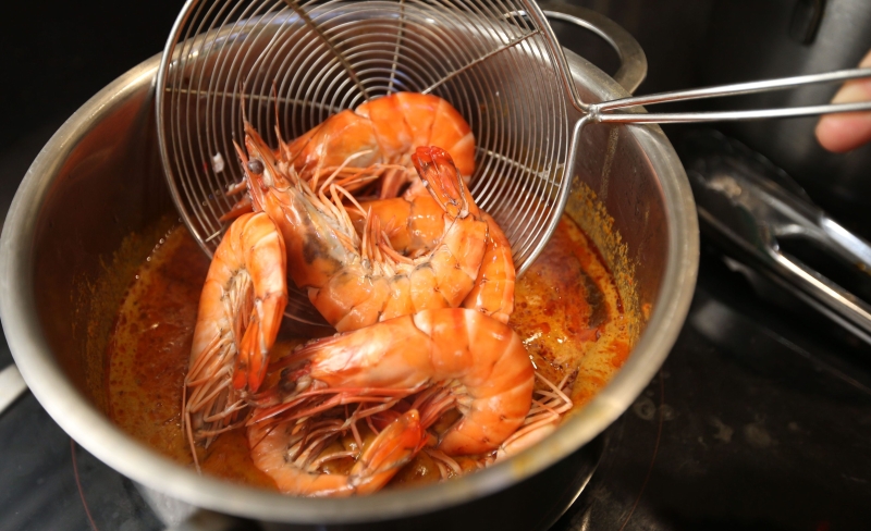 2.提前熬煮咖喱汤汁，并把汆烫后的虾只放入汤内煮一会儿。