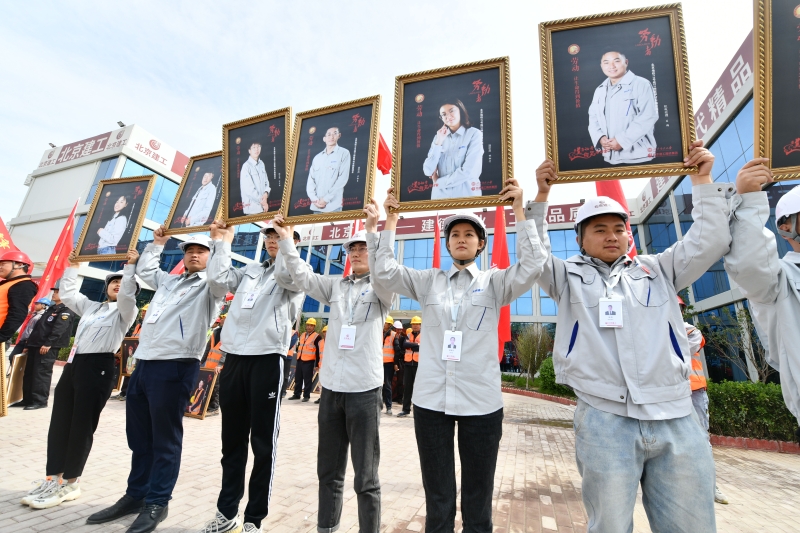北京“五一劳动竞赛”参与者们高举著他们微笑的肖像。（ 新华社照片）