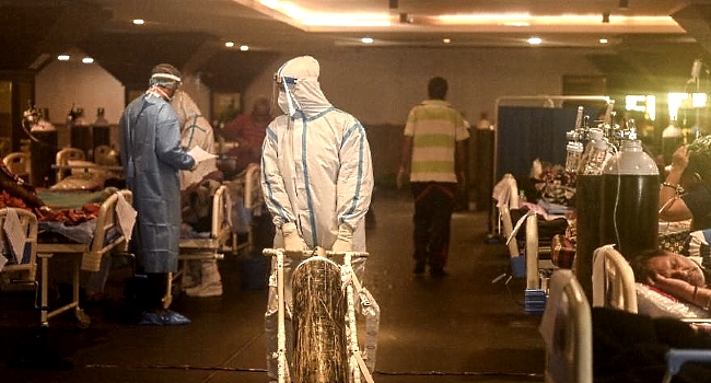 Health workers wearing personal protective equipment attend to Covid-19 coronavirus positive patients inside a banquet hall temporarily converted into a Covid-19 care center in New Delhi. AFP