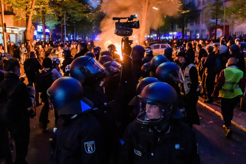 在德国首都柏林，入夜后仍有大批人聚集，有示威者焚烧杂物，警察防守并拍摄记录。（图：欧新社）